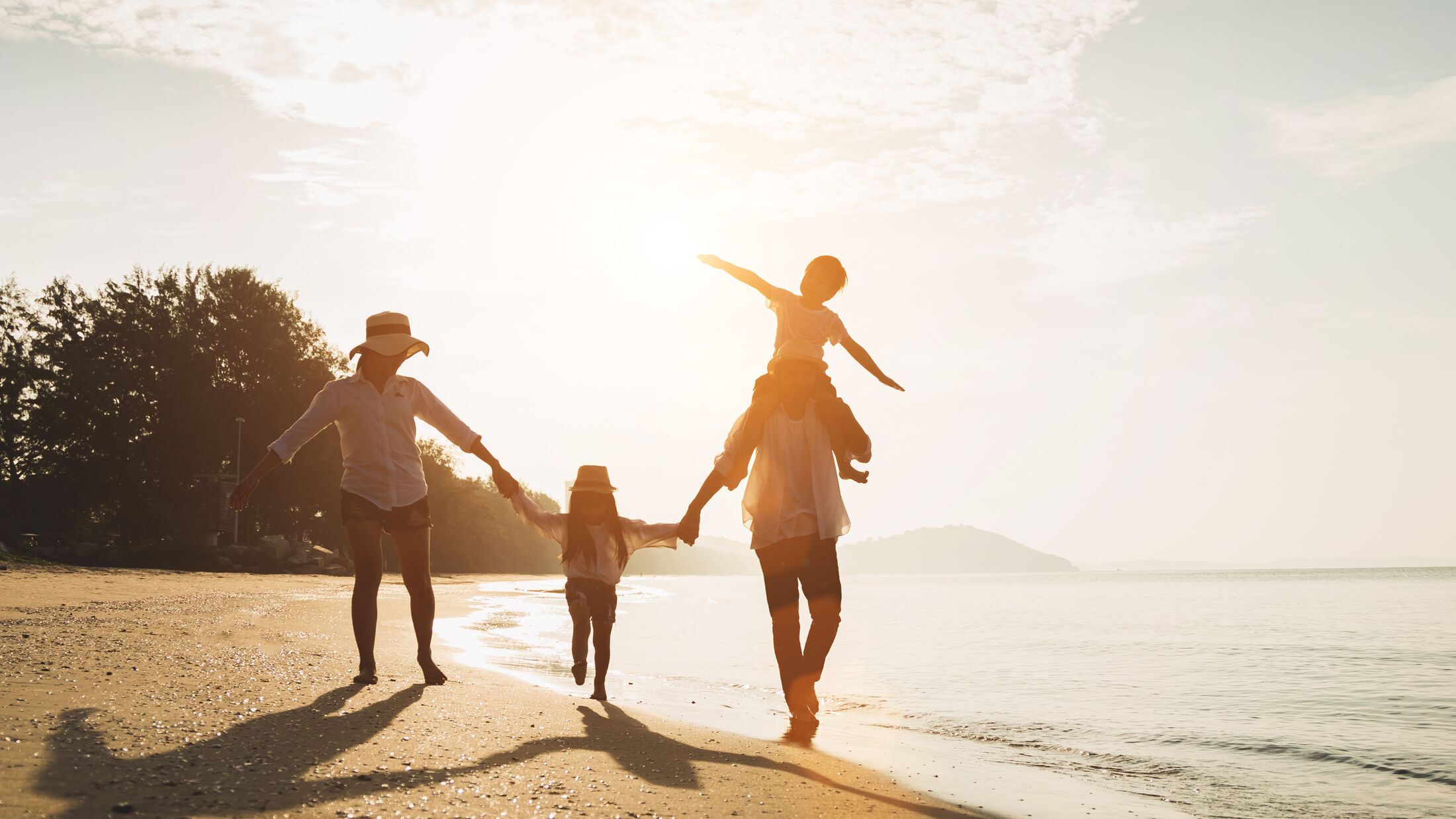 Happy family travel on beach in holiday,Summer vacations. Happy family are having fun on a tropical beach in sunset. Father and mother and children playing together outdoor on beach.