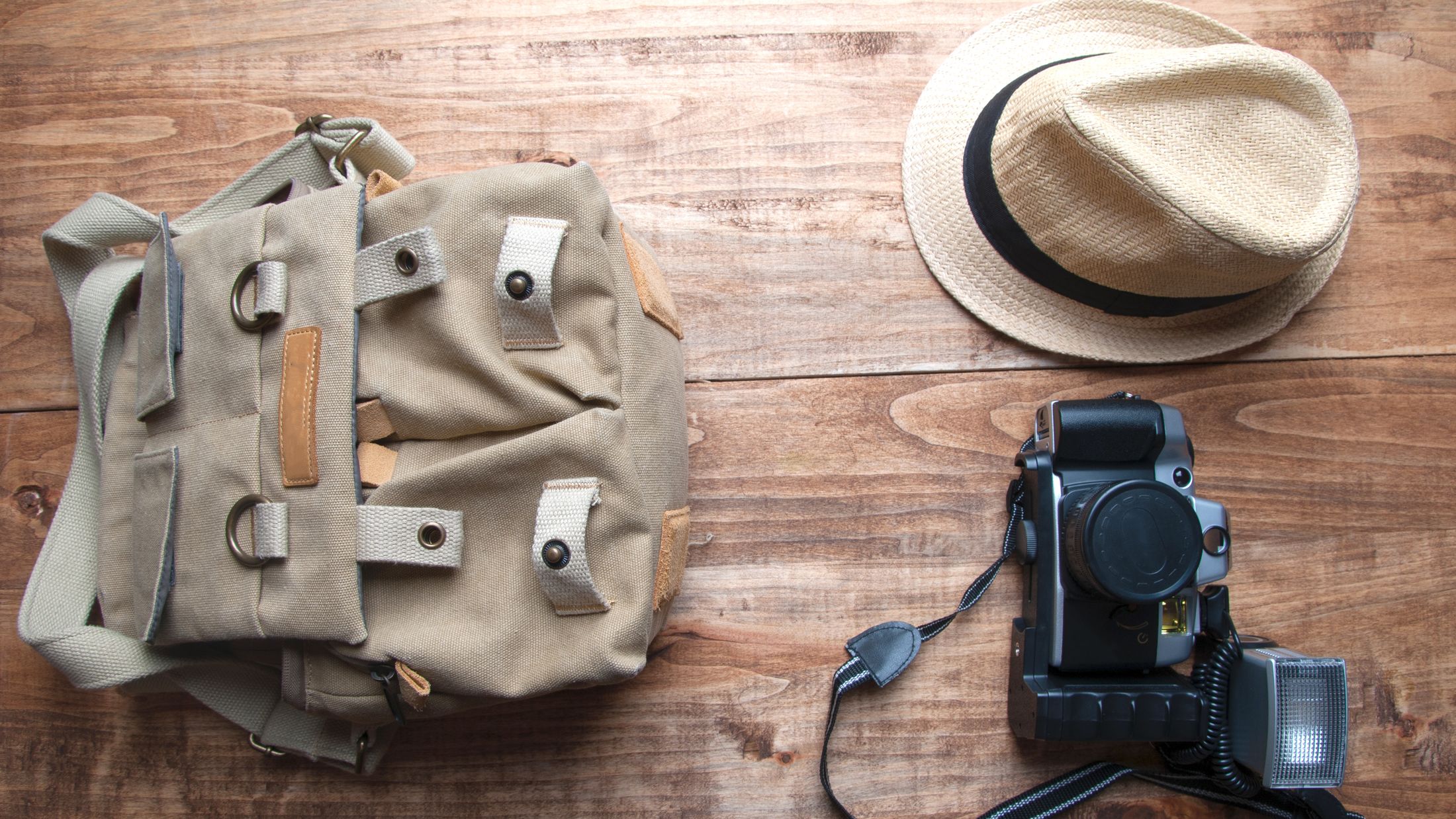 Tourism concept. Backpack, hat , binocular and old camera isolated on wooden background.; Shutterstock ID 437880175; PO: Project Italy - Facilities images; Job: Project Italy - Facilities images; Client: H&J/Citalia