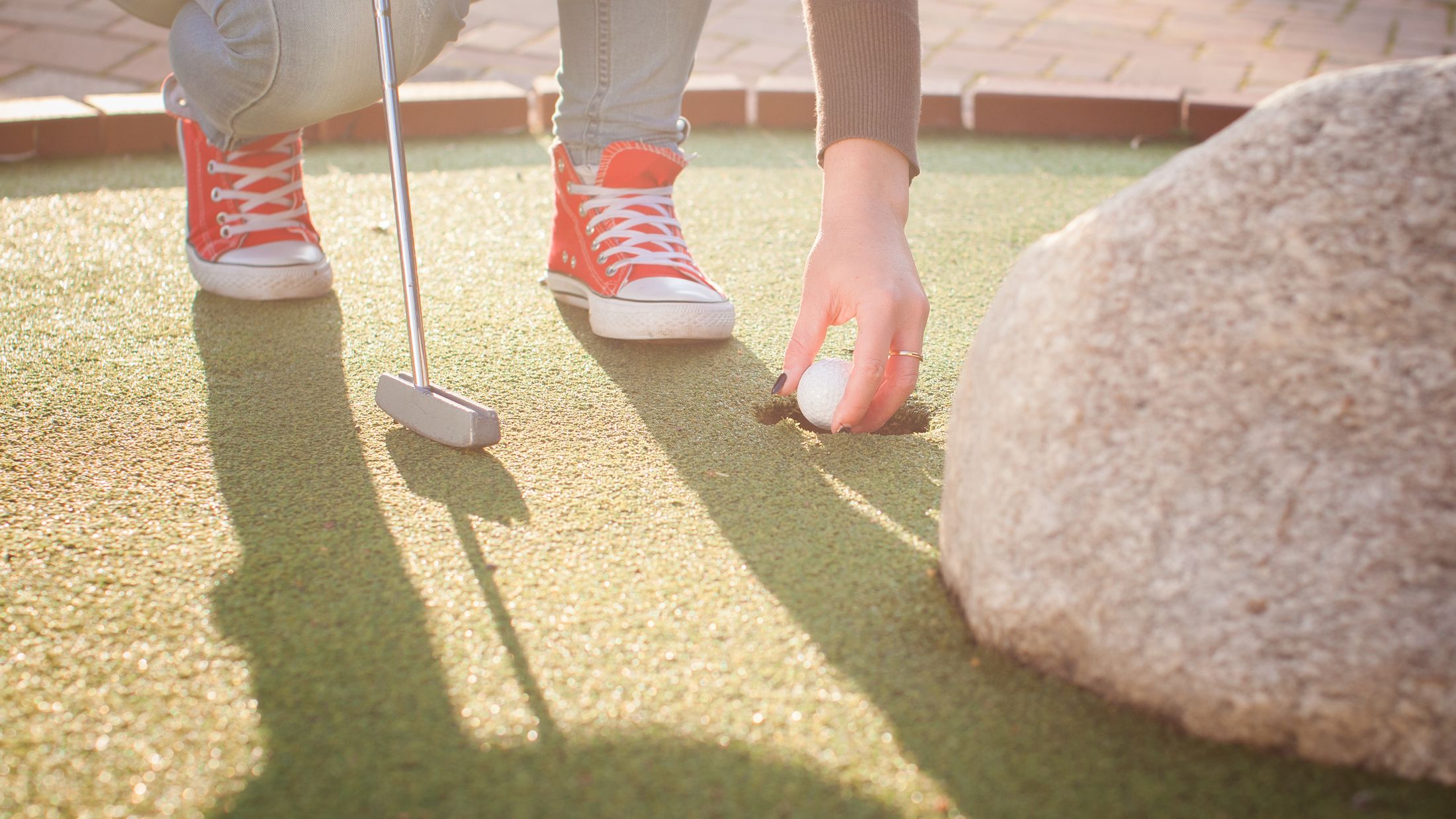 Detail of young woman playing mini/adventure golf on a beautiful sunny summer day (colorful image, photo was taken in warm evening light); Shutterstock ID 219627934; PO: Project Italy - Facilities images; Job: Project Italy - Facilities images; Client: H&J/Citalia