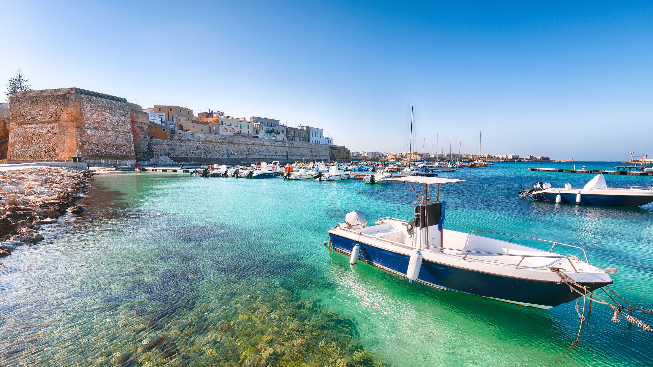 Several fishing boats at the Otranto harbour - coastal town in Puglia with turquoise sea. Italian vacation. Town Otranto, province of Lecce in the Salento peninsula, Puglia, Italy