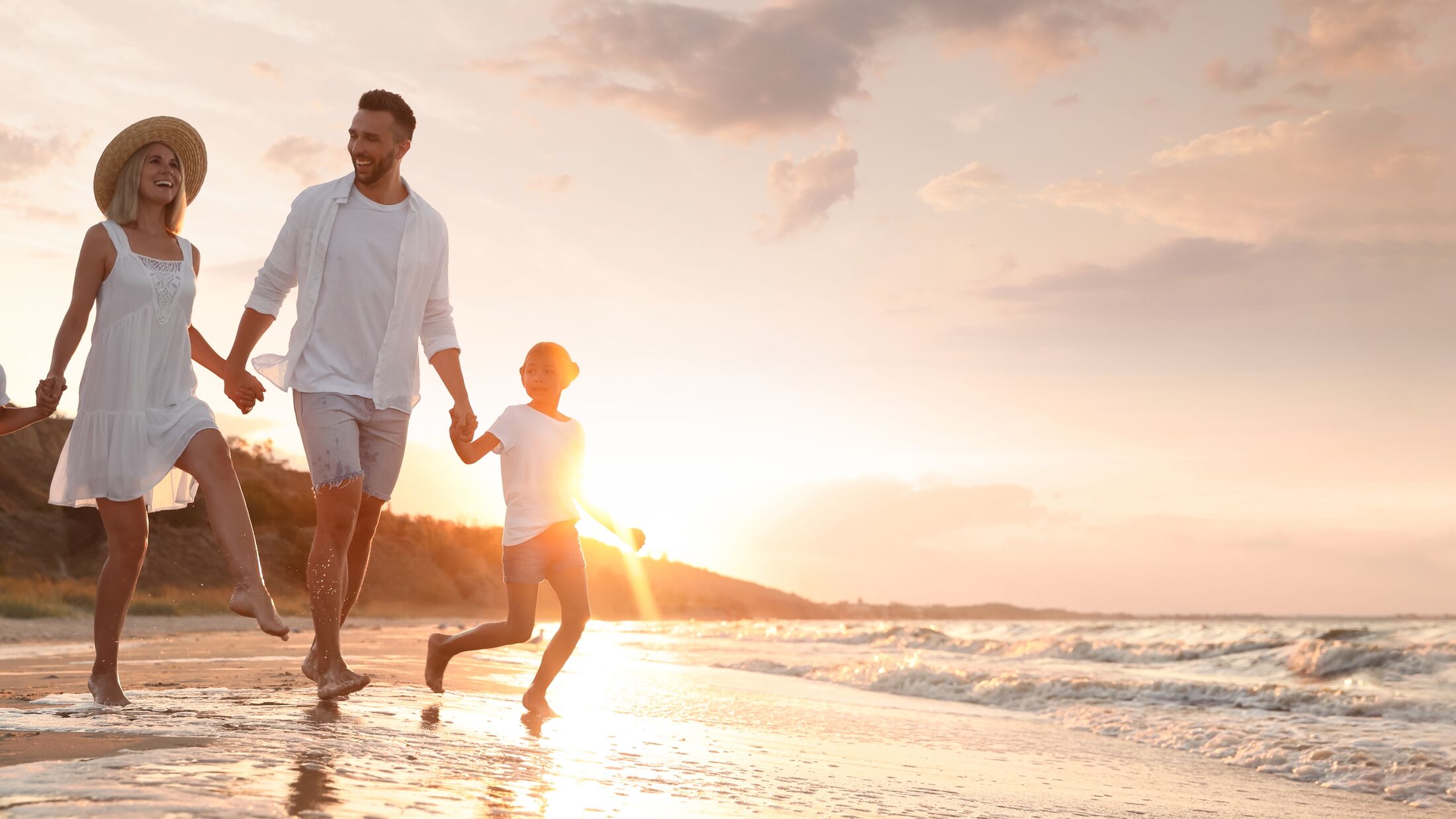 Happy family running on sandy beach near sea at sunset, space for text. Banner design