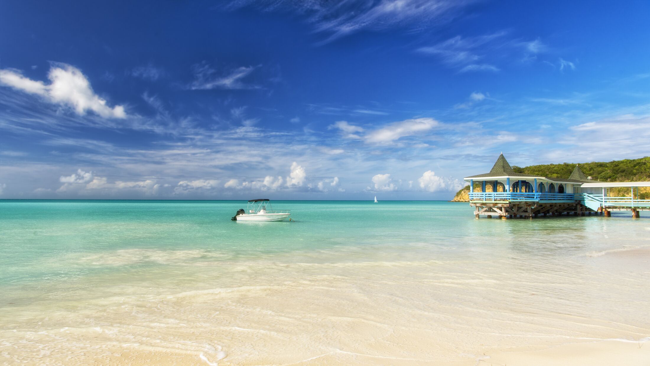 Exotic beautiful marine beach of Antigua St. Johns with one wave runner on water and house with small clouds in sunny sky outdoor on natural background