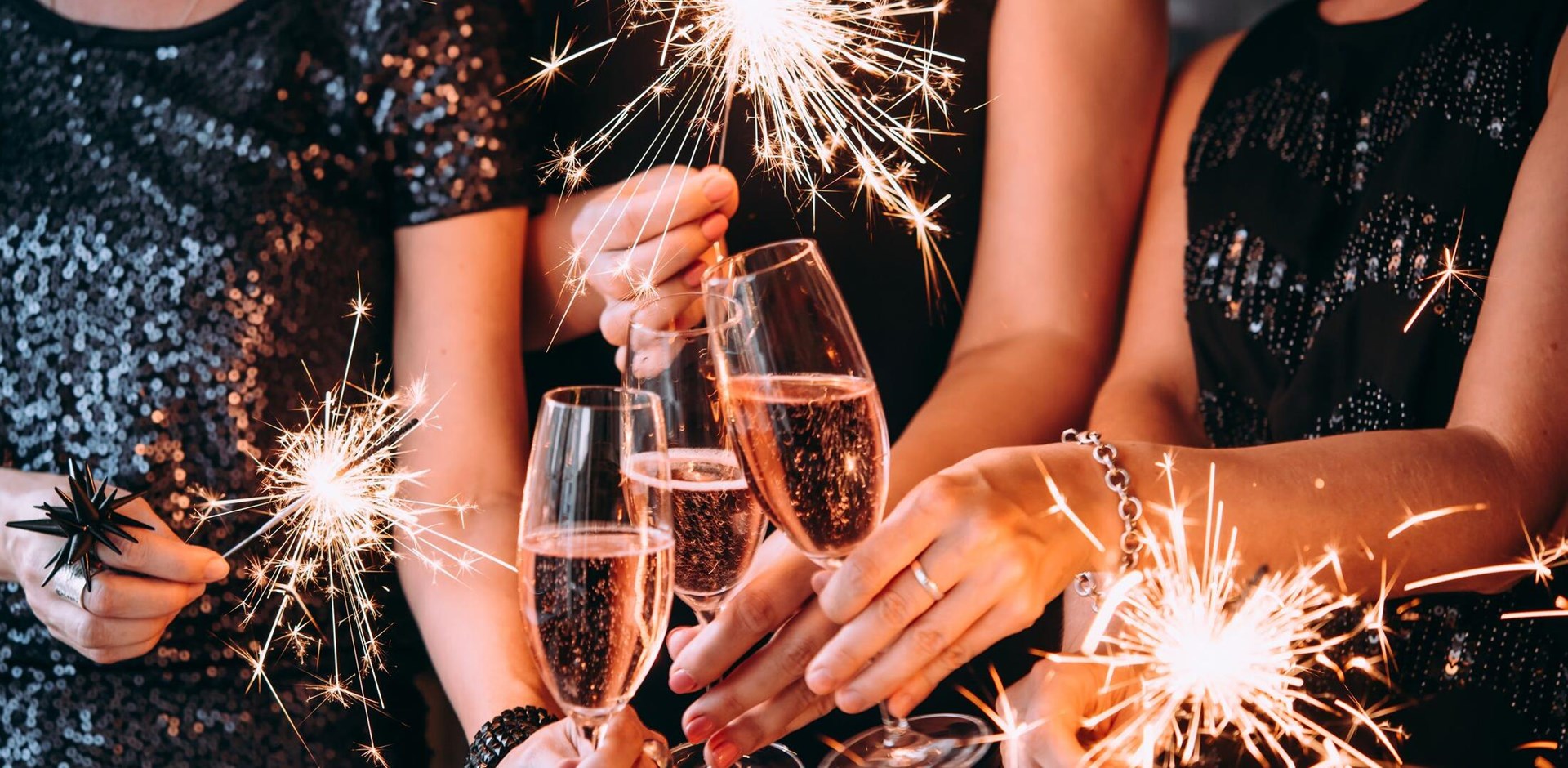 Friends celebrating Christmas or New Year eve party with Bengal lights and rose champagne.