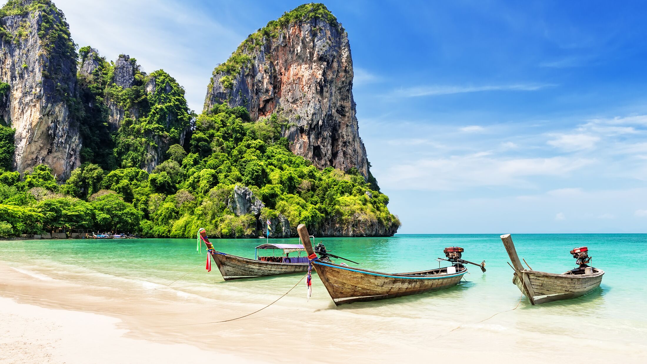 Thai traditional wooden longtail boat and beautiful sand Railay Beach in Krabi province. Ao Nang, Thailand.