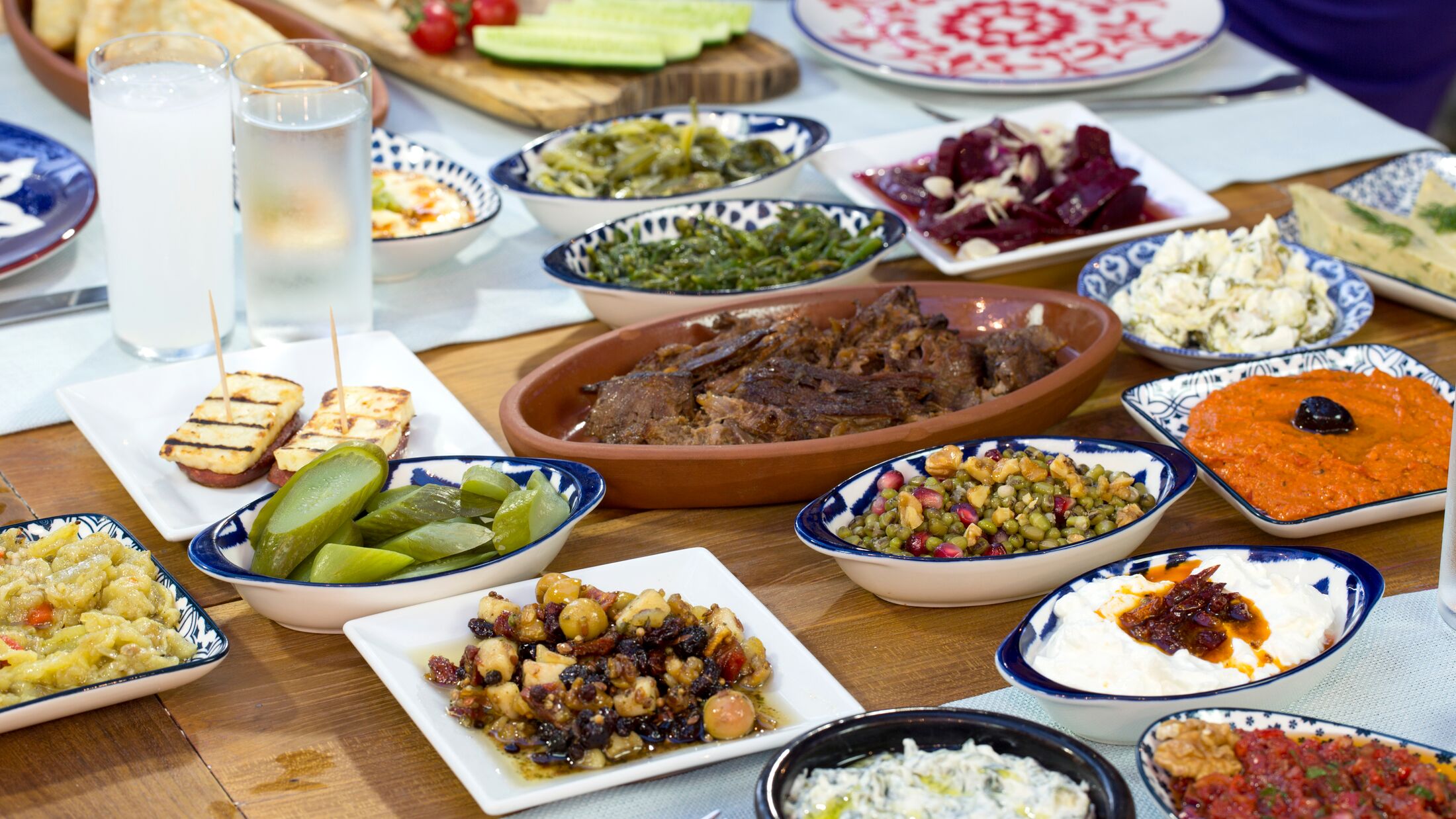 Luxury table with plate of fish, meat, pickles, antipasto, aubergine, appetizers, cheese, mezze, salad, octopus, raki and ouzo. Copy space for text area.